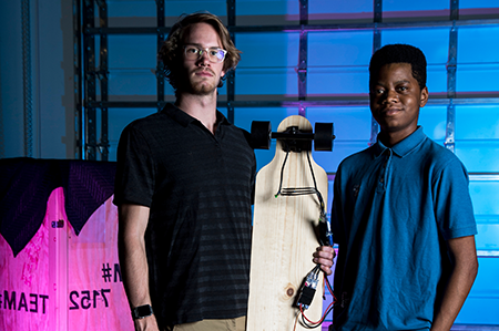 Two male students standing with skateboard